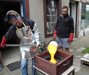 hot glass casting_pouring hot glass into a sand mold